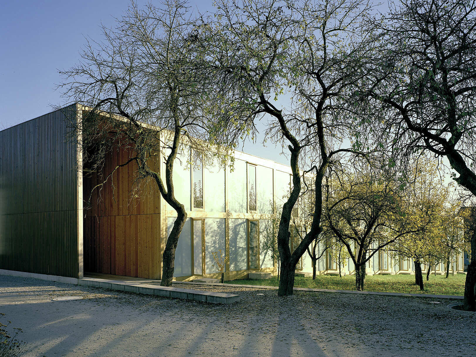 Biohotel Apfelgarten exterior — KAPILUX W panels glowing among bare apple trees