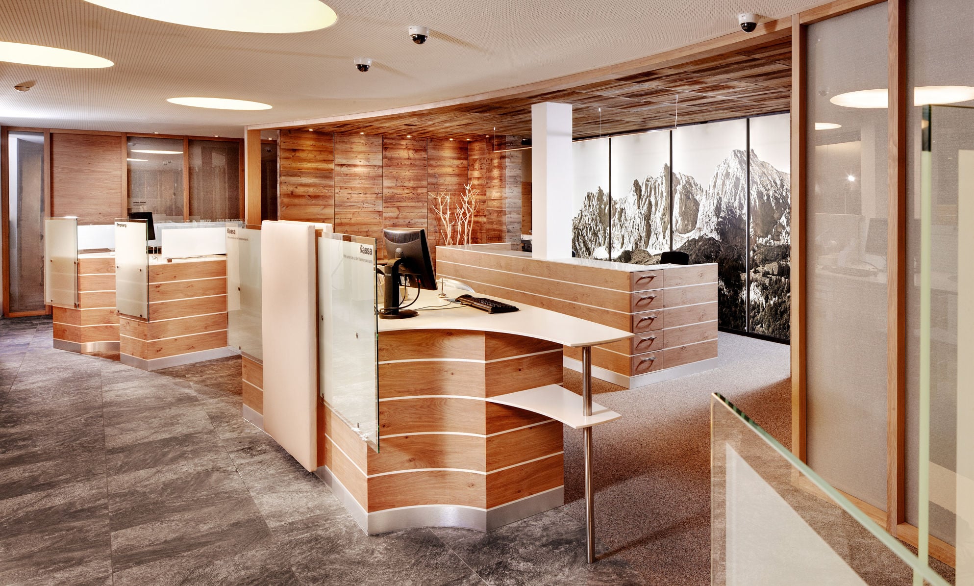 RRB Raiffeisen Regionale Bank, St. Johann in Tirol — KAPILUX T interior glazing in two-story atrium with wood-framed partitions