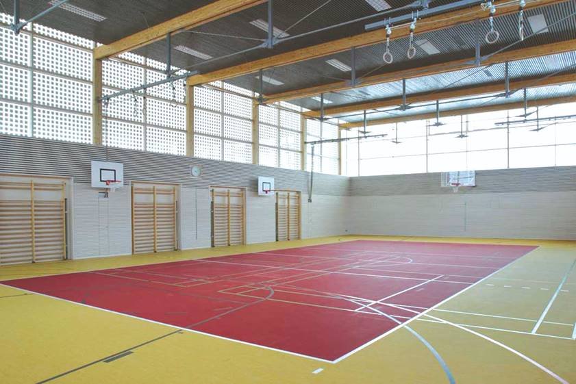 German school gymnasium with OKACELL clerestory glazing, photovoltaic band delivering diffuse daylight to athletic court