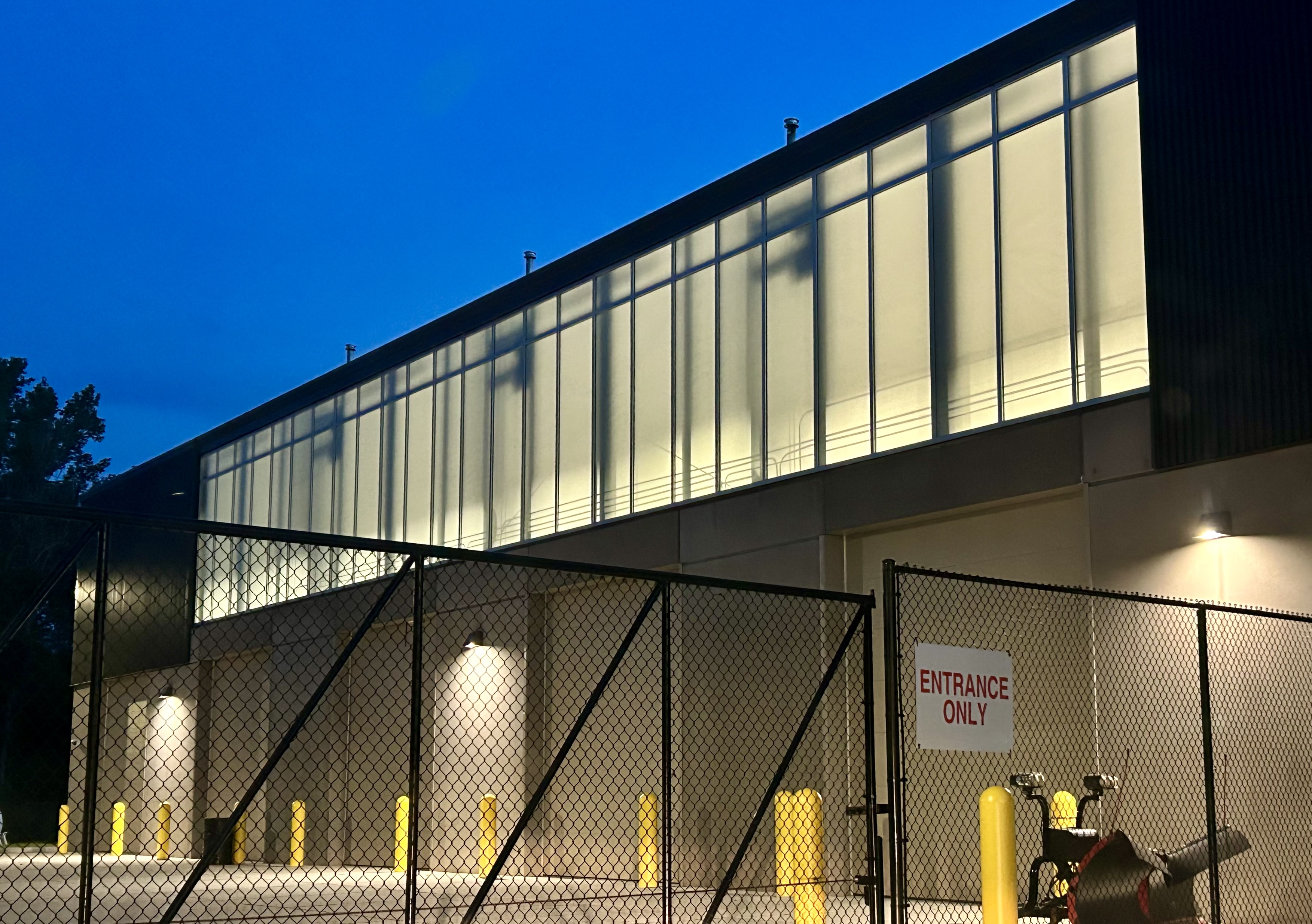 Lewis Central Operations facility at dusk, Council Bluffs NE — OKALUX clerestory band glowing as continuous lantern across facade