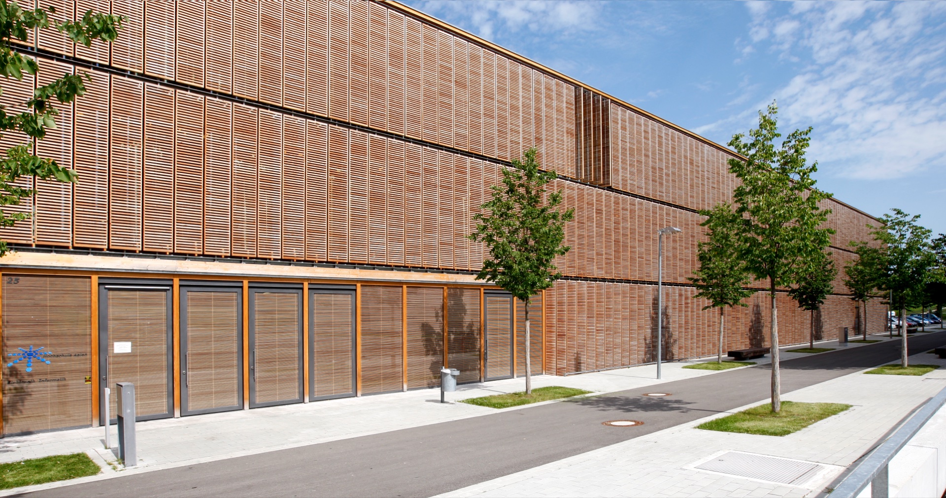 Aalen Fachhochschule — full OKAWOOD envelope across three floors, horizontal wood-slat ribs in IGU