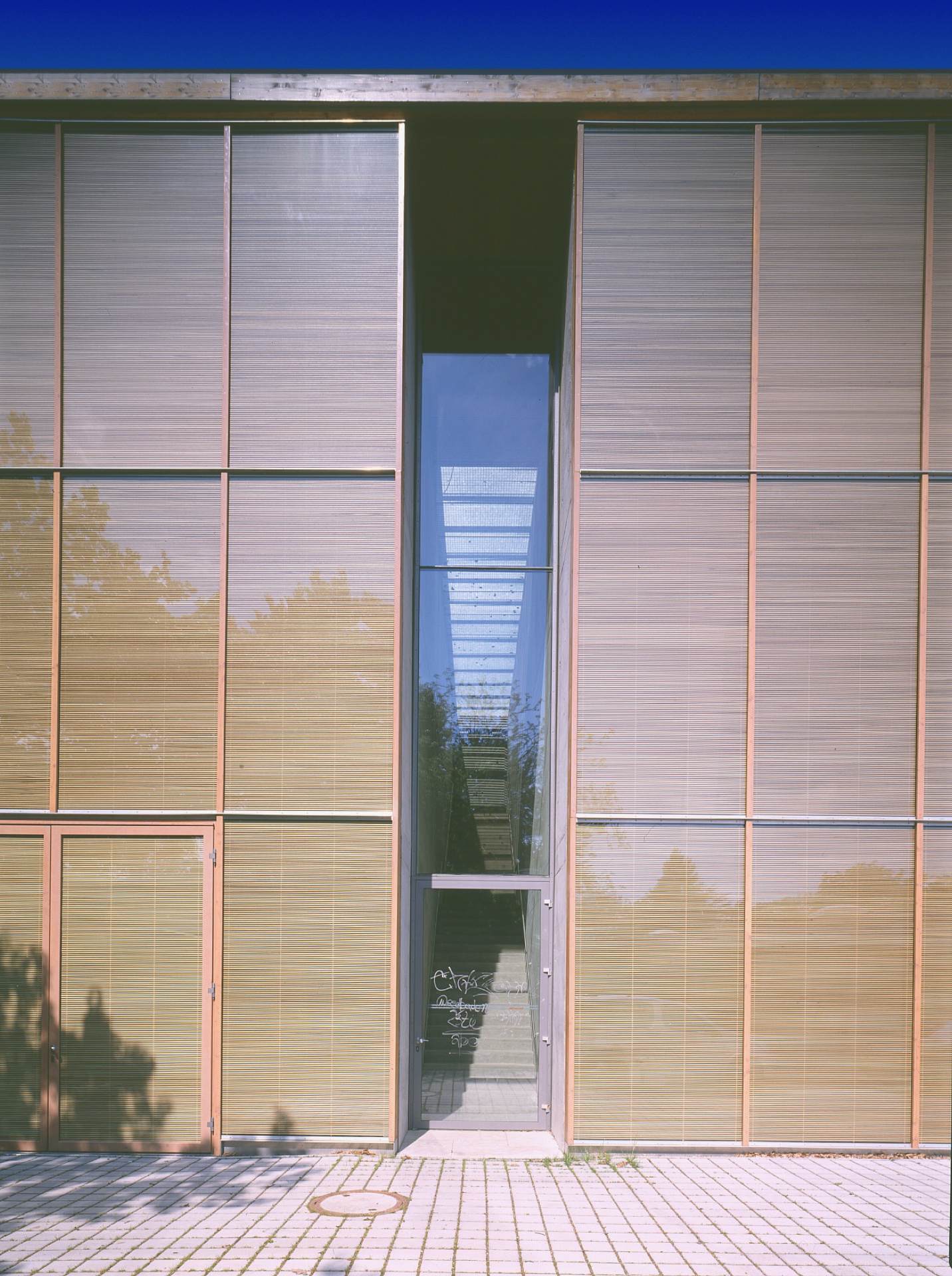 Wiesbaden Fachhochschule south elevation — OKAWOOD corner wrap, two facades, wood ribs against blue sky